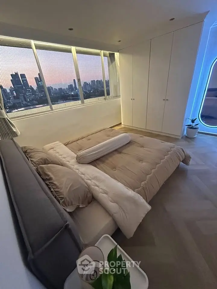 Luxurious bedroom with stunning city skyline view and modern furnishings.