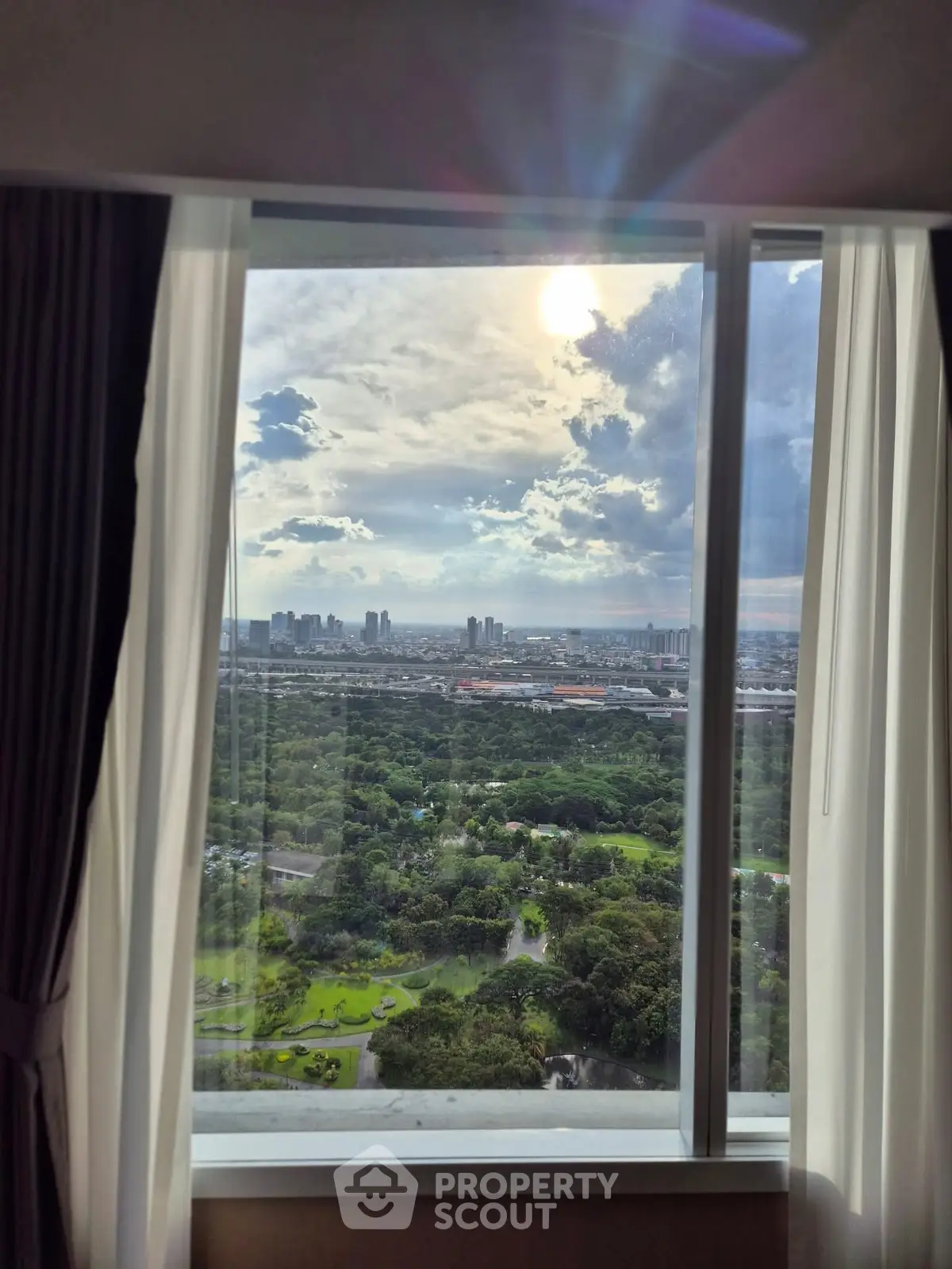 Stunning high-rise view of city skyline and lush greenery from a large window.