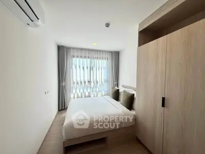 Modern bedroom with large window and stylish wardrobe in a bright apartment.
