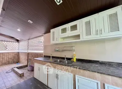 Spacious outdoor kitchen with modern cabinetry and dual sink, perfect for entertaining guests.