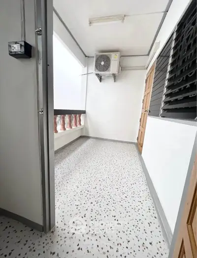Spacious balcony with air conditioning unit and terrazzo flooring in modern apartment.