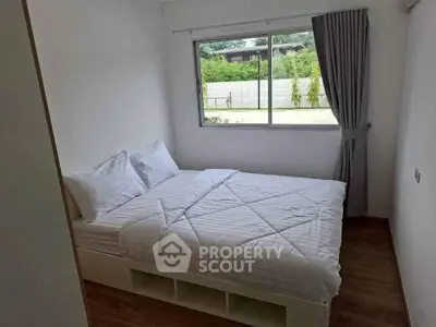 Cozy bedroom with large window and modern decor, perfect for relaxation and comfort.