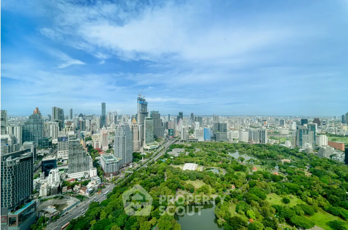 Stunning aerial view of city skyline with lush green park and skyscrapers under blue sky.