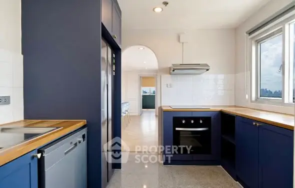 Modern kitchen with sleek blue cabinets and built-in appliances, featuring a bright open layout.