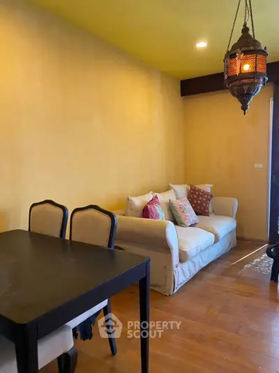 Charming living room with cozy sofa and elegant dining table, featuring warm lighting and wooden flooring.