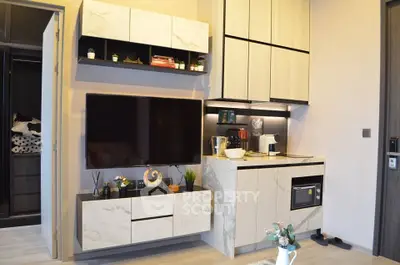 Modern living room with sleek cabinetry and wall-mounted TV in stylish apartment.