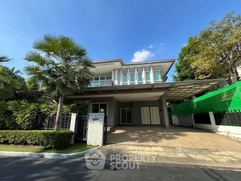 Stunning modern two-story house with lush greenery and spacious driveway.