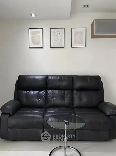Modern living room with sleek black leather sofa and stylish wall art