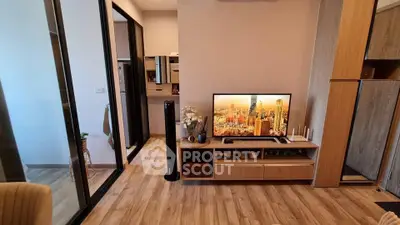 Modern living room with wooden flooring and stylish TV setup in a cozy apartment.