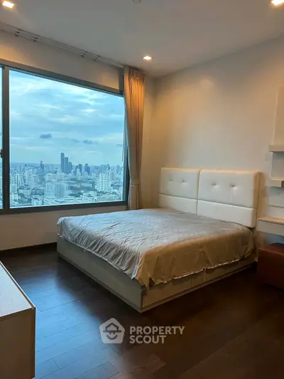 Luxurious bedroom with stunning city view and modern furnishings in high-rise apartment.