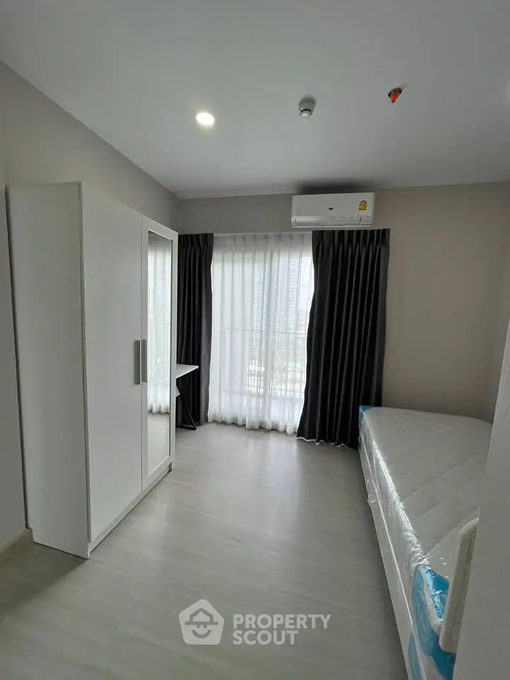 Modern bedroom with minimalist design, featuring a bed, wardrobe, and large window with city view.