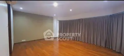 Spacious empty room with wooden flooring and large curtains, ideal for customization.