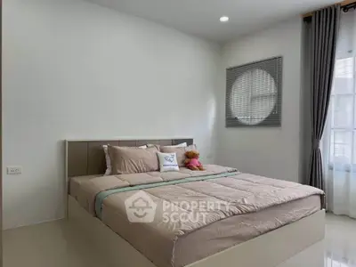 Cozy bedroom with modern decor and natural light, featuring a plush bed and stylish window treatments.