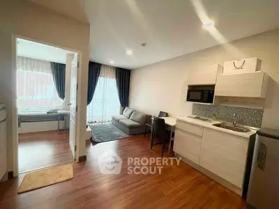 Modern open-plan living room and kitchen with wooden flooring and natural light.