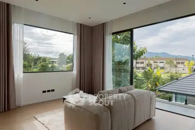 Spacious living room with large windows offering stunning views of lush greenery and mountains.