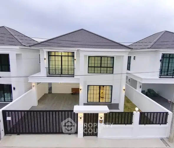 Modern two-story white house with gated entrance and spacious driveway.