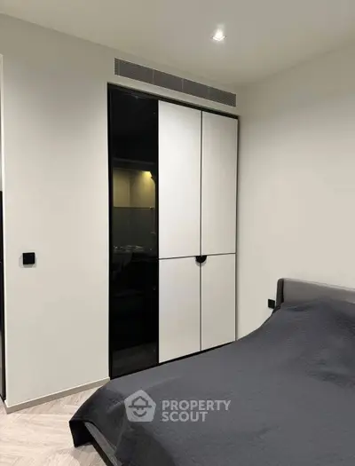 Modern bedroom with sleek wardrobe and cozy bedding in a contemporary apartment.
