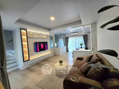 Modern living room with stylish decor and open layout, featuring a cozy sofa and large TV unit.