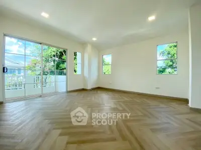 Spacious living room with elegant herringbone flooring and large windows offering natural light.