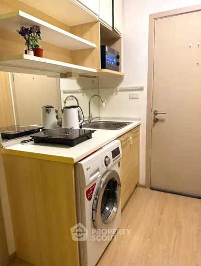 Compact kitchen with washing machine and modern appliances in cozy apartment.