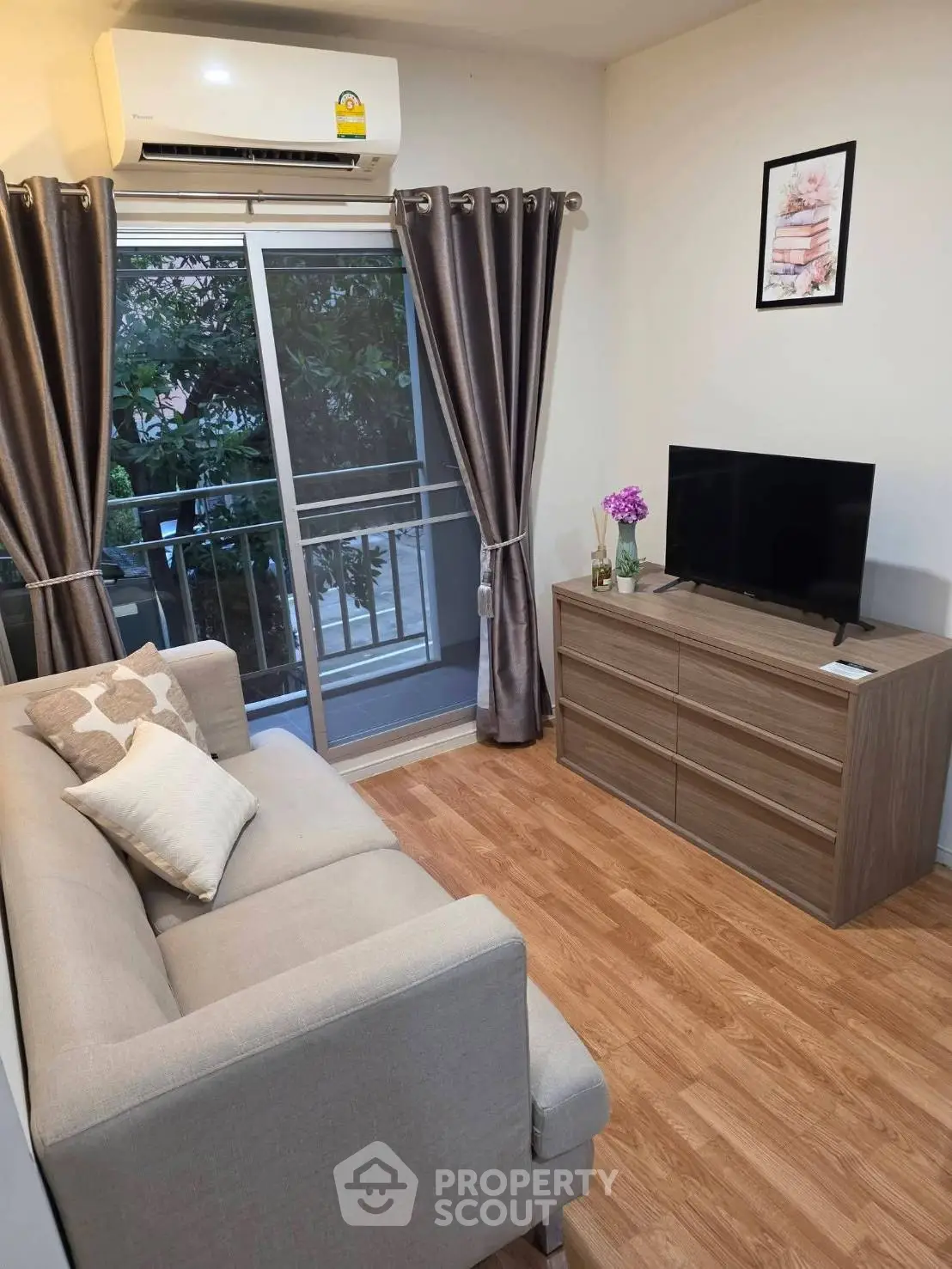Cozy living room with modern decor, featuring a comfortable sofa, flat-screen TV, and balcony access.