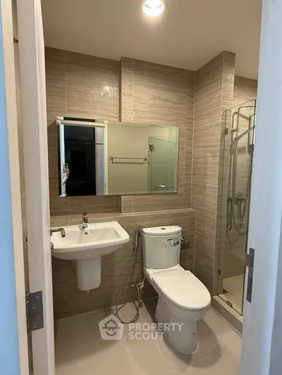 Modern bathroom with sleek fixtures and glass shower enclosure in a contemporary apartment.