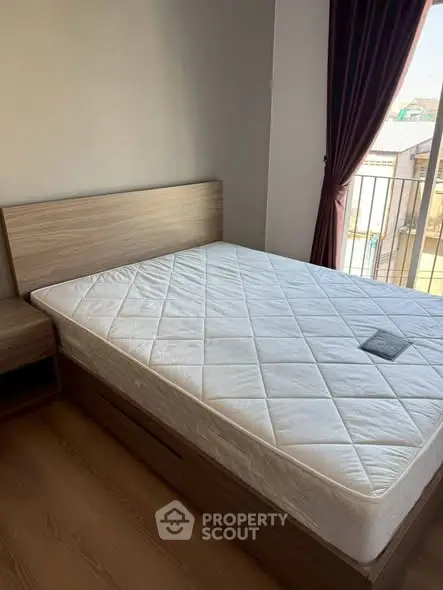 Cozy bedroom with wooden bed frame and balcony view, perfect for relaxation.
