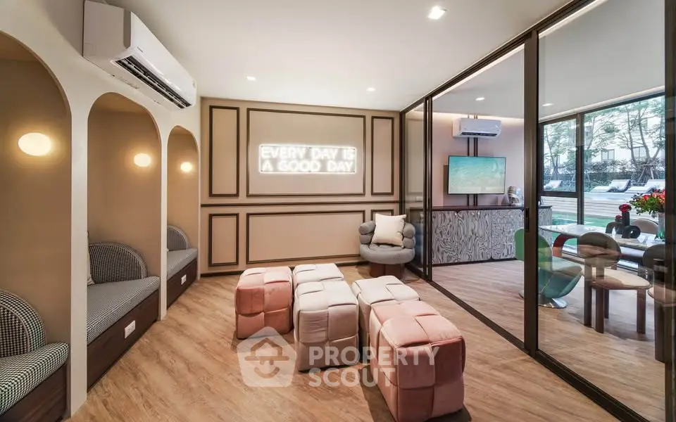 Modern living room with stylish seating and neon sign, featuring glass partition and wooden flooring.