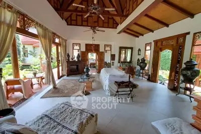 Spacious living room with high wooden ceilings and garden view, featuring elegant decor and natural light.