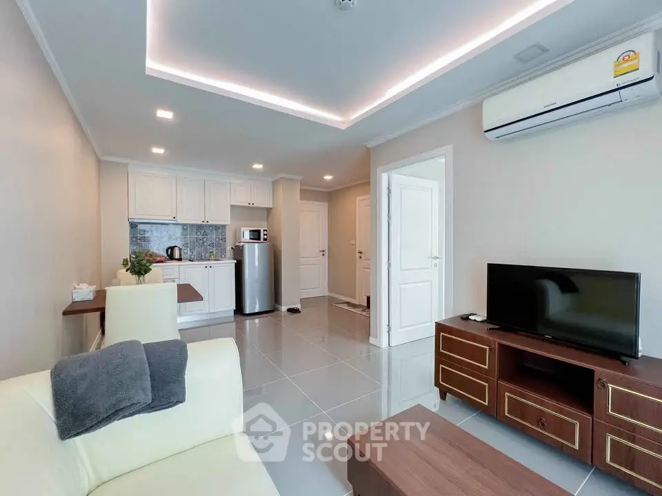Modern living room with open kitchen, sleek furniture, and air conditioning unit.