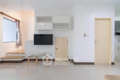 Modern living room with minimalist design, featuring a wall-mounted TV and sleek glass coffee table.