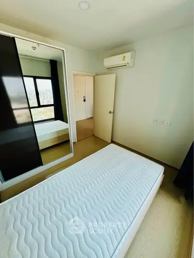 Bright bedroom with large window and mirrored closet in modern apartment.