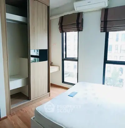 Modern bedroom with large windows and built-in wardrobe in a stylish apartment.