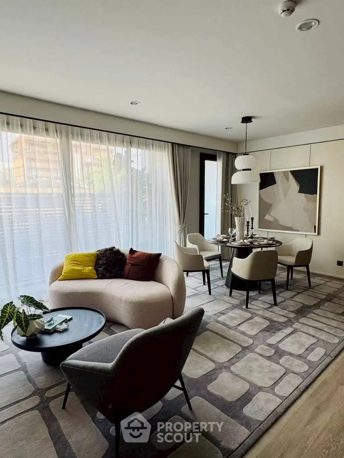 Elegant living room with modern decor and dining area, featuring large windows and stylish furniture.