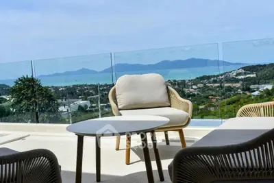 Stunning balcony view with modern outdoor seating overlooking scenic landscape and ocean.