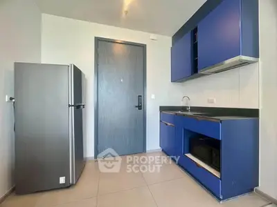 Modern kitchen with sleek blue cabinets and stainless steel fridge in a minimalist design.