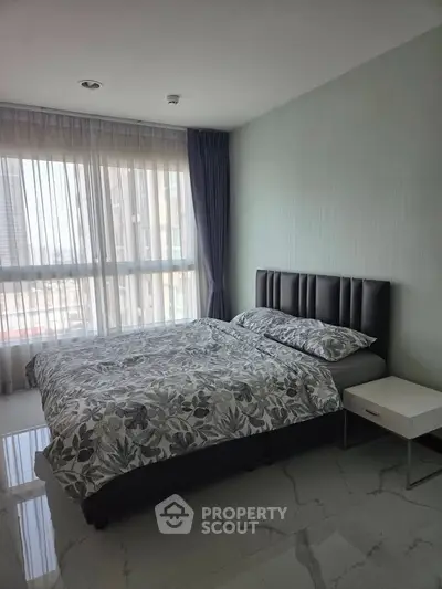 Modern bedroom with large window and stylish decor in a high-rise apartment.