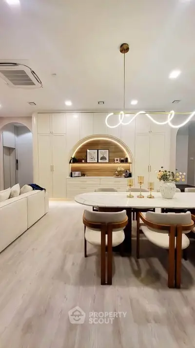Elegant modern living room with stylish dining area and built-in shelving, featuring contemporary lighting and decor.