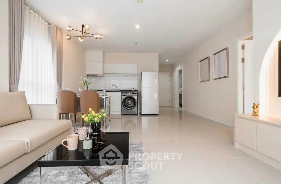 Modern open-plan living room with kitchen, featuring sleek furniture and bright natural lighting.