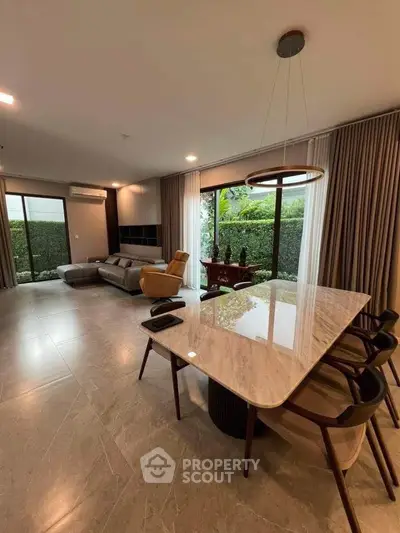 Spacious modern living room with elegant marble dining table and garden view.