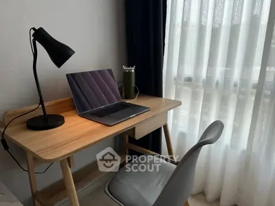 Modern study nook with sleek desk, laptop, and stylish chair by a sunlit window.