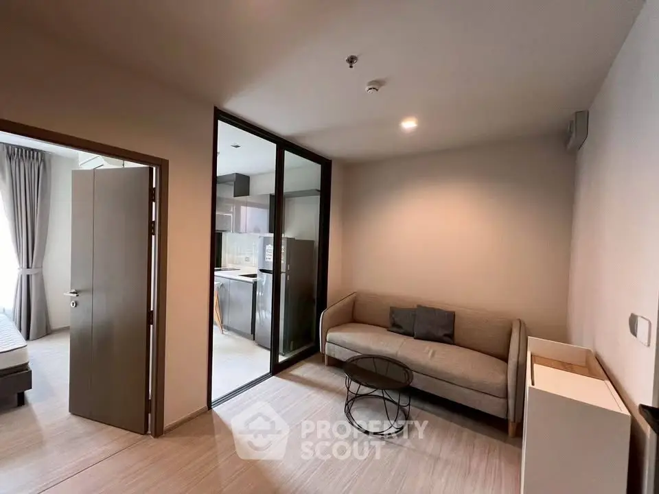 Modern living room with cozy sofa and open kitchen layout in stylish apartment.