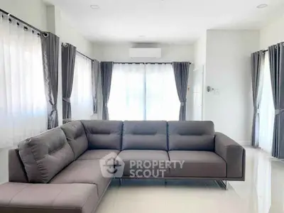 Spacious living room with modern L-shaped sofa and large windows.