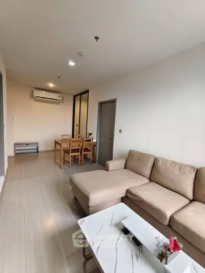 Modern living room with beige sofa and dining area in open layout apartment