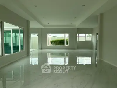 Spacious modern living room with large windows and glossy marble floors.