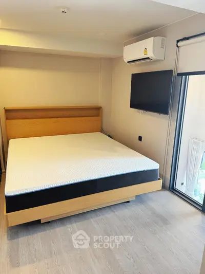 Modern bedroom with large bed, wall-mounted TV, and air conditioning unit