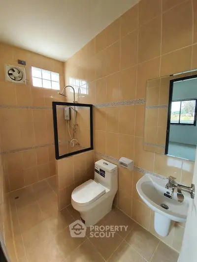 Modern bathroom with beige tiles and sleek fixtures, featuring a shower and toilet.