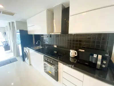 Modern kitchen with sleek black countertops and appliances in open layout.