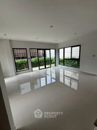 Spacious modern living room with large windows and glossy tiled floor.