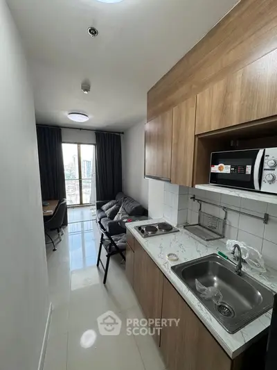 Modern compact kitchen and living area with city view in high-rise apartment